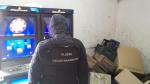 Funkcjonariusz służby celno-skarbowej w trakcie kontroli zaplecza sklepu spożywczego z nielegalnymi automatami do gier