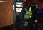 Dwóch umundurowanych funkcjonariuszy służby celno-skarbowej w lokalu przed automatem do nielegalnych gier hazardowych