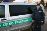 funkcjonariusz służby celno-skarbowej stoi przy aucie służbowym
