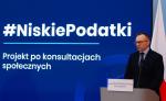 Minister Artur Soboń podczas konferencji na tle banera z napisem Niskie Podatki - projekt po konsultacjach społecznych