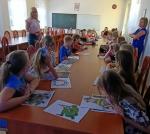 Dzieci siedzą przy stole i uczestniczą w lekcji