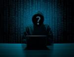 Grafika na tle ściany z cyframi w ciemnym stroju siedzi przed laptopem człowiek w bluzie z kapturem na twarzy, której nie widać a na jej miejscu jest znak zapytania.