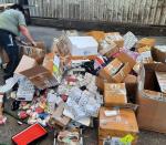 Funkcjonariuszka pochylona nad podrobionymi produktami, rozrzuconymi tuż przed zniszczeniem.