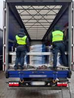 Otwarta ciężarówka, w środku beczki, a tyłem stoją funkcjonariusze