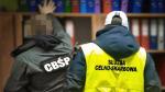 funkcjonariusze KAS i CBŚP stoją przed regałem z segregatorami