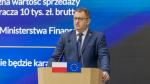 Marcin Łoboda szef Krajowej Administracji Skarbowej przy mównicy z flagami Polski i Unii Europejskiej