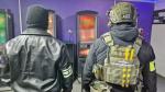 funkcjonariusz Służby Celno-Skarbowej i funkcjonariusz Policji stoją w lokalu pośród nielegalnych automatów do gier 