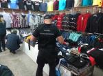 Funkcjonariusz KAS w trakcie czynności kontrolnych w kołobrzeskim sklepie z podrabianą odzieżą