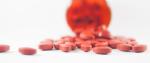 czerwone tabletki wysypujące się z opakowania