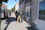 Funkcjonariusze Policji oraz Zachodniopomorskiej KAS stoją  przed wejściem do salonu gier komputerowych w Dębnie